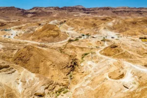 The Judaean Desert landscape with rugged, arid hills and dry valleys under a clear sky.