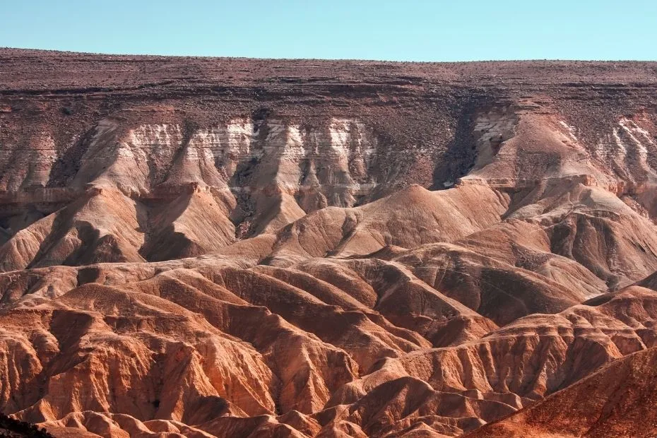 The Negev Desert features rugged, reddish mountains and cliffs with sparse vegetation.
